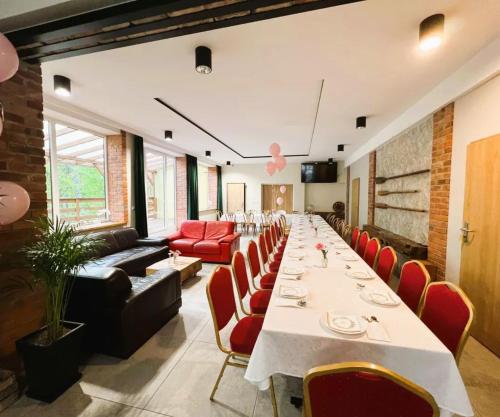 a long dining room with a long table and red chairs at 3 WIOSŁA Brzozowa Zatoka in Brenno