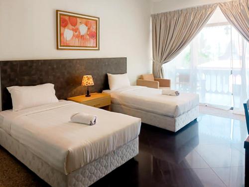 a hotel room with two beds and a window at Putera Island Resort in Melaka