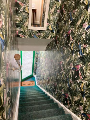 a staircase with a mural of plants on the wall at The loft in Lincolnshire
