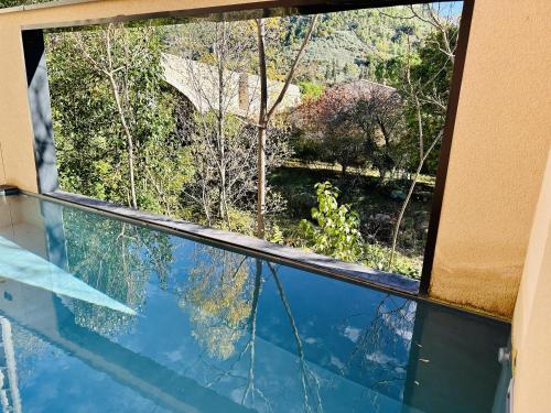 une fenêtre avec vue sur un reflet dans l'eau dans l'établissement L'Oasis de Syam en Provence, à Buis-les-Baronnies