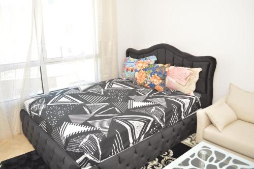 a bedroom with a black bed with a black and white comforter at Cheap Professional Beautiful Studio Apartment in Bobigny