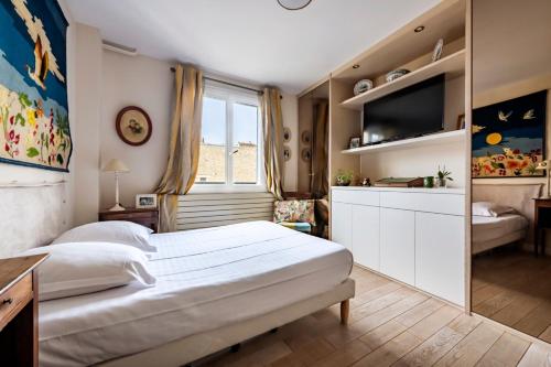 une chambre avec un grand lit blanc et une télévision dans l'établissement Veeve - Hidden Heaven, à Paris