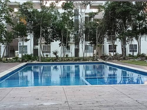 a blue swimming pool in front of a building at Departamento en CanCun. in Cancún
