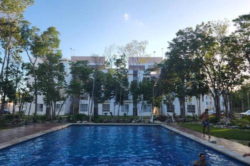 a large swimming pool in front of a white building at Departamento en CanCun. in Cancún