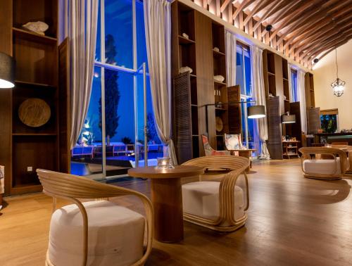 a living room with a table and chairs and a large window at Aquila Elounda Village Resort, Suites & Spa in Elounda