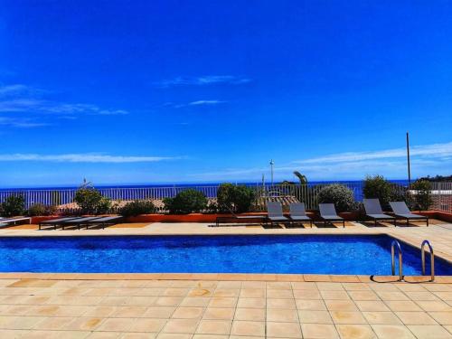 une piscine avec des chaises et l'océan en arrière-plan dans l'établissement 2 pièces face à la mer, à Théoule-sur-Mer