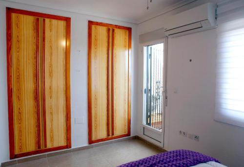 a bedroom with three wooden doors and a window at Bungalow Gran Alacant in Gran Alacant
