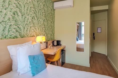 a hotel room with a bed and a desk at Hôtel Du Centre, un hôtel AMMI in Nice