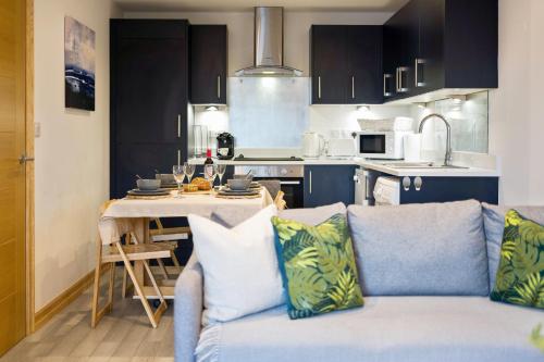 a living room with a blue couch and a kitchen at Large, newly renovated, three bedroom TOWN CENTRE split level apartment with free parking, sleeps seven - Walking distance to beach in Bournemouth