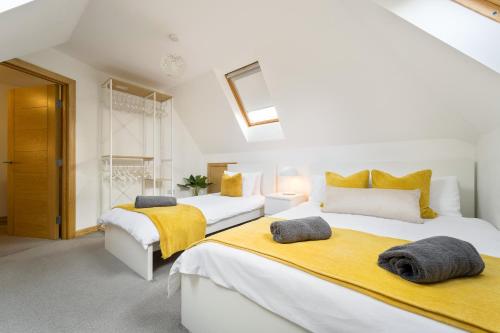two beds in a white room with yellow blankets at Large, newly renovated, three bedroom TOWN CENTRE split level apartment with free parking, sleeps seven - Walking distance to beach in Bournemouth