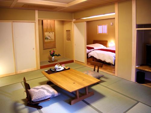 a living room with a table and a bed at Gero Onsen Yukyunohana in Gero