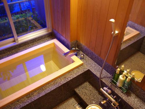 a bathroom with a bath tub with a sink at Gero Onsen Yukyunohana in Gero