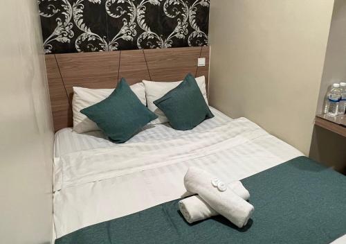 a bed with green pillows and a towel on it at KUANTAN BESERAH BUDGET HOTEL in Kuantan