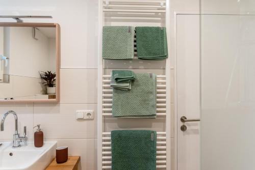 een badkamer met groene handdoeken en een wastafel bij Ruhige Ferienwohnung „Südhang“ direkt am Wald in Bad Arolsen