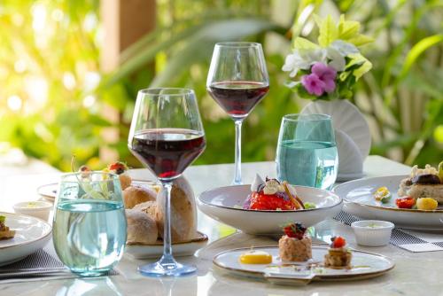 a table with glasses of wine and plates of food at Atmosphere Kanifushi - Premium All Inclusive with Free Transfers in Lhaviyani Atoll