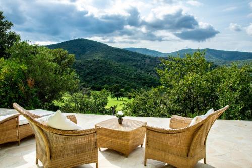 eine Terrasse mit Korbstühlen, einem Tisch und Bergen in der Unterkunft Esprit du Sud Fionna in Roquebrune-sur-Argens