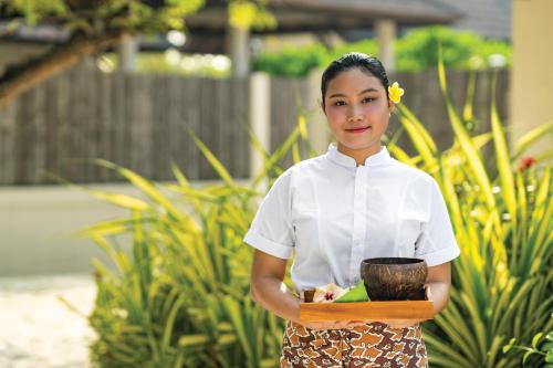 a woman in a white shirt holding a bowl at Atmosphere Kanifushi - Premium All Inclusive with Free Transfers in Lhaviyani Atoll