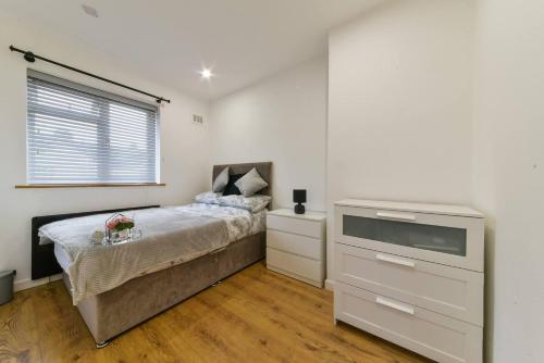 a bedroom with a bed with a dresser and a window at Beckenham Place - Free Parking - Self Check-in in Bromley
