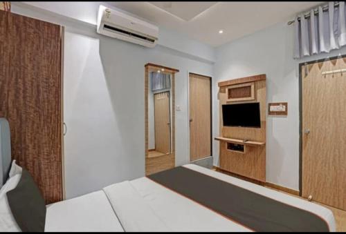 a room with a bed and a television and a kitchen at Hotel Privilege View in Ahmedabad
