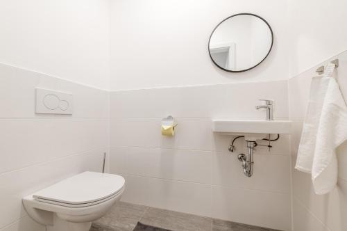 a white bathroom with a toilet and a mirror at Mountain View - by myNests in Gröbming