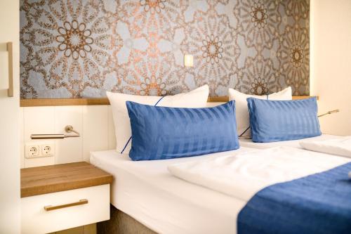 a bedroom with two beds with blue pillows at Hotel Zur Seemöwe in Kirchdorf