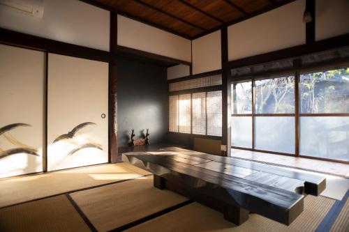 a room with a large bench in front of windows at お宿でん吉 in Minami Aso