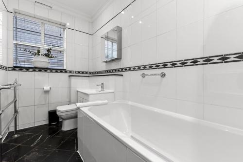 ロンドンにある2 Bedroom Apartment- Mayfair (1)の白いバスルーム(バスタブ、トイレ付)