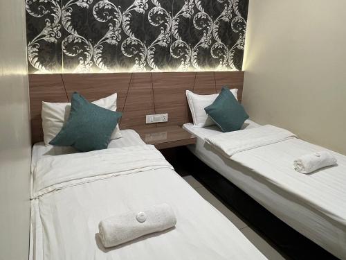 two beds in a hotel room with white and blue pillows at KUANTAN BESERAH BUDGET HOTEL in Kuantan