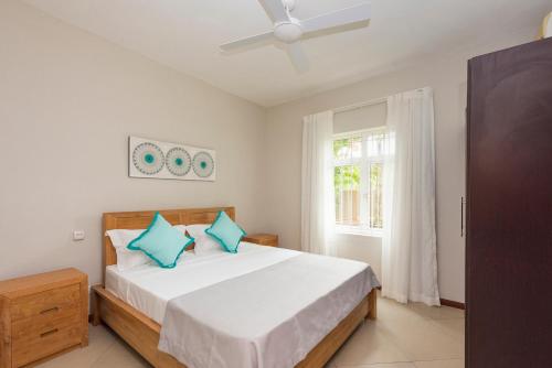 ein Schlafzimmer mit einem Bett mit blauen Kissen und einem Fenster in der Unterkunft Kisana Residence - Lovely 2 Bedroom Apartment - Pointe aux Canonniers in Pointe aux Cannoniers