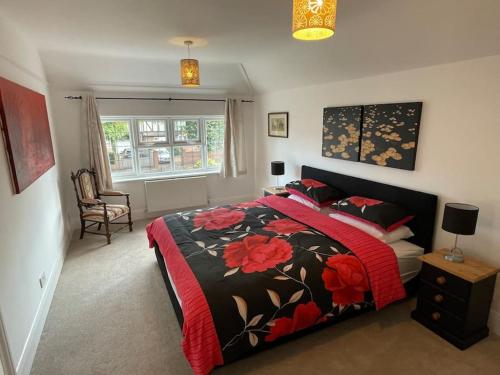 Spacious 3 bedroom house in heart of Hampton Court في إيست موليسي: غرفة نوم بسرير وبطانية حمراء وسوداء