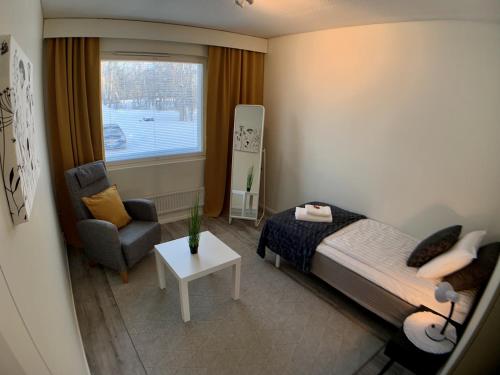 ein Schlafzimmer mit einem Bett, einem Stuhl und einem Fenster in der Unterkunft Kaupunkikoti in Kemi