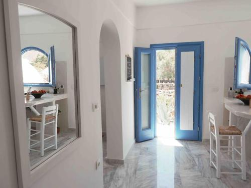 a hallway with a blue door and a mirror at Villa Nidito Santorini in Vlychada Beach