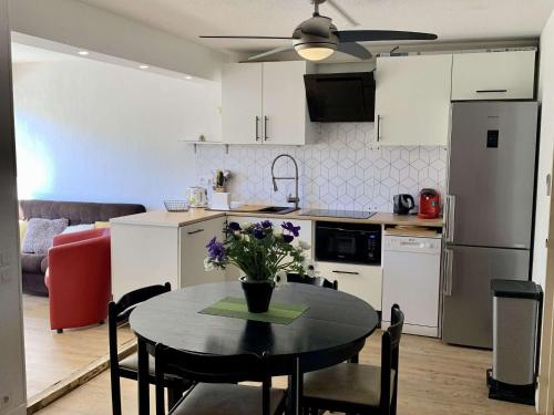 - une cuisine avec une table ornée de fleurs violettes dans l'établissement Charmant T3 rénové, jardin privatif, plage à pied, clim, parking, 4 pers. - FR-1-607-153, au Cap d'Agde