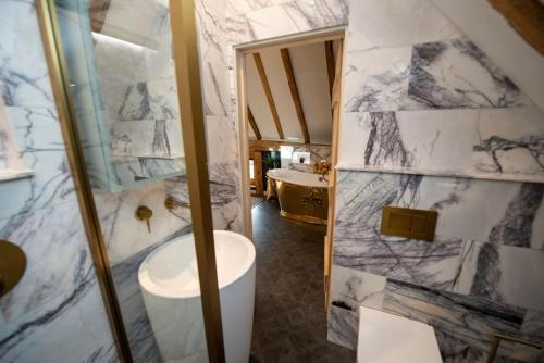 a bathroom with a shower and a white marble wall at Cloth Hall Barn & Cottages in Smarden