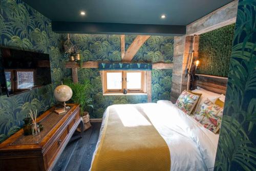 a bedroom with a large bed in a room with green wallpaper at Cloth Hall Barn & Cottages in Smarden