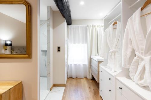 baño con armarios blancos y espejo en Château Coraline, 