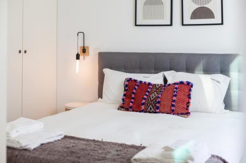 um quarto com uma cama com lençóis brancos e almofadas em FLH Bairro Alto Balcony with River View em Lisboa