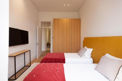 a hotel room with two beds and a flat screen tv at FLH Príncipe Real Luxury Spacious Apartment in Lisbon