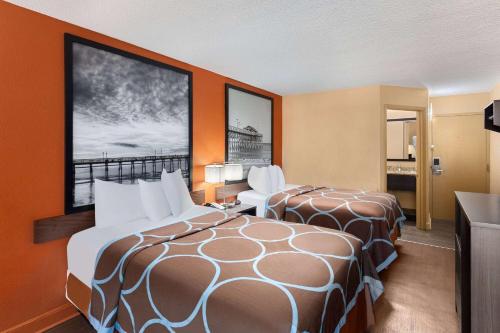 two beds in a hotel room with orange walls at Super 8 by Wyndham Myrtle Beach/Market Common Area in Myrtle Beach