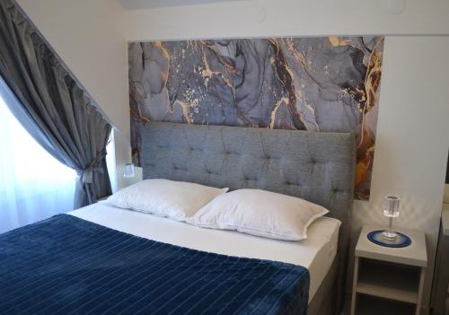 a bedroom with a bed with a blue blanket and white pillows at Apartman "INSOMNIA" u samom centru grada, udaljen 100 metara od glavnog gradskog trga, sa BESPLATNIM PARKIRALIŠTEM !!! in Slavonski Brod
