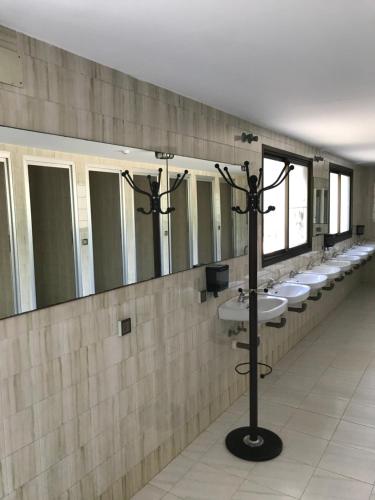uma casa de banho com uma fila de lavatórios e espelhos em Camping peregrino San marcos em Santiago de Compostela