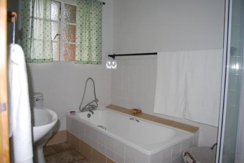 a bathroom with a bath tub and a toilet at Urban Bush Lodge in Howick