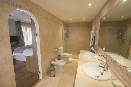 a bathroom with two sinks and a toilet and a mirror at Villa Near Beach in Marbella with Heated Pool in Marbella