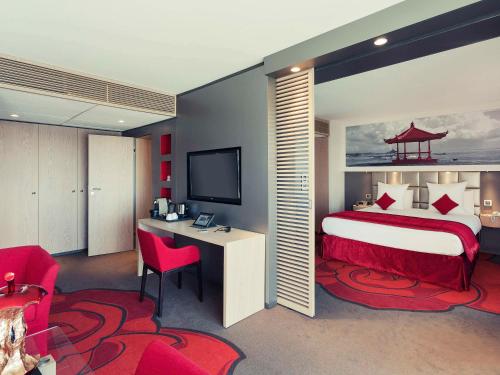 een slaapkamer met een bed, een bureau en een televisie bij Mercure Orléans Centre Bords de Loire in Orléans