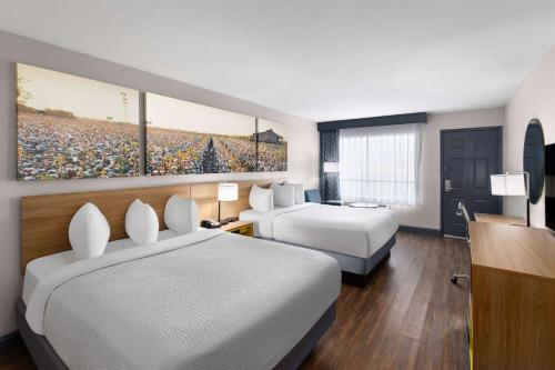 a hotel room with two beds and a television at Days Inn by Wyndham Carlisle in Carlisle