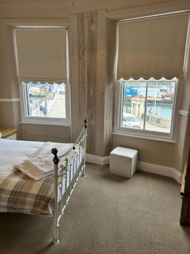 a bedroom with a bed and two windows at Admiral MacBride in Plymouth