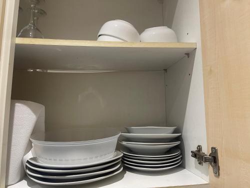 a cabinet filled with plates and bowls on a shelf at the woodland apartment 1 in London