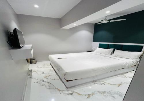 a bedroom with a large white bed and a tv at Grand Dyad Hotel - Near Kokilaben Hospital Andheri West in Mumbai