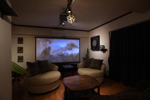 a living room with a large screen tv and chairs at CINEMA RESORTS 4 in Motobu