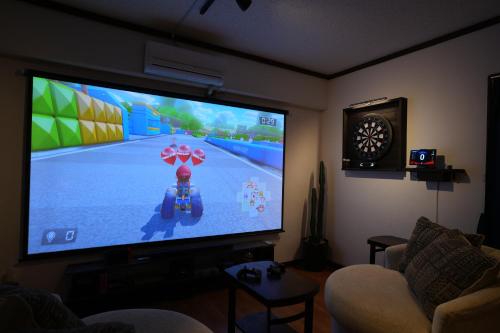 a living room with a large television with a video game on it at CINEMA RESORTS 4 in Motobu